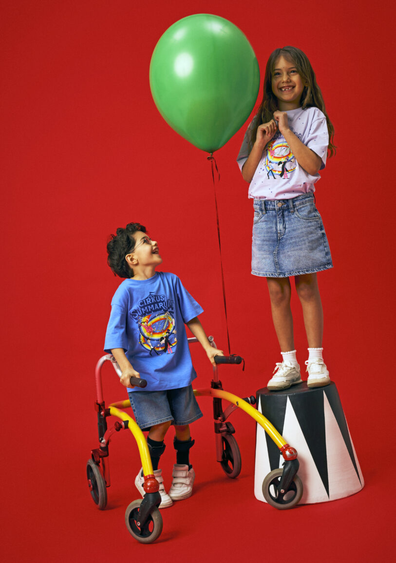 To børn i den officielle Cirkus Summarum 2026 T-shirt fra name it. Den ene T-shirt er blå med Cirkus Summarum motiv foran, den anden T-shirt er lilla med stjernetryk og Cirkus Summarum motiv foran.